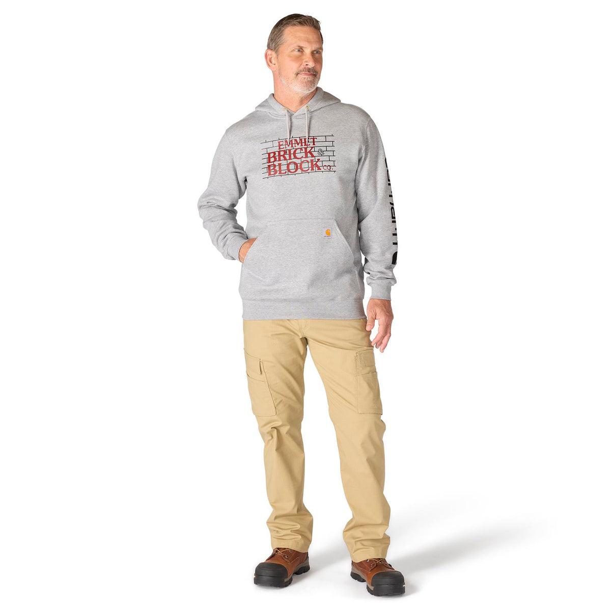 Man wearing a gray hoodie with text and beige pants on a white background